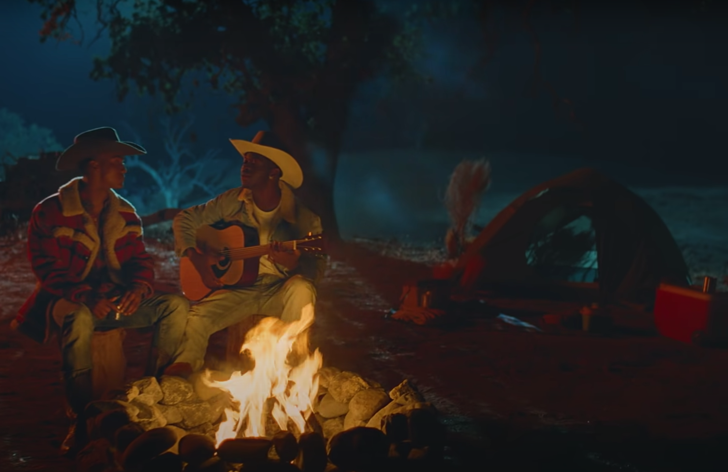 Nas and his lover sitting at a campfire.