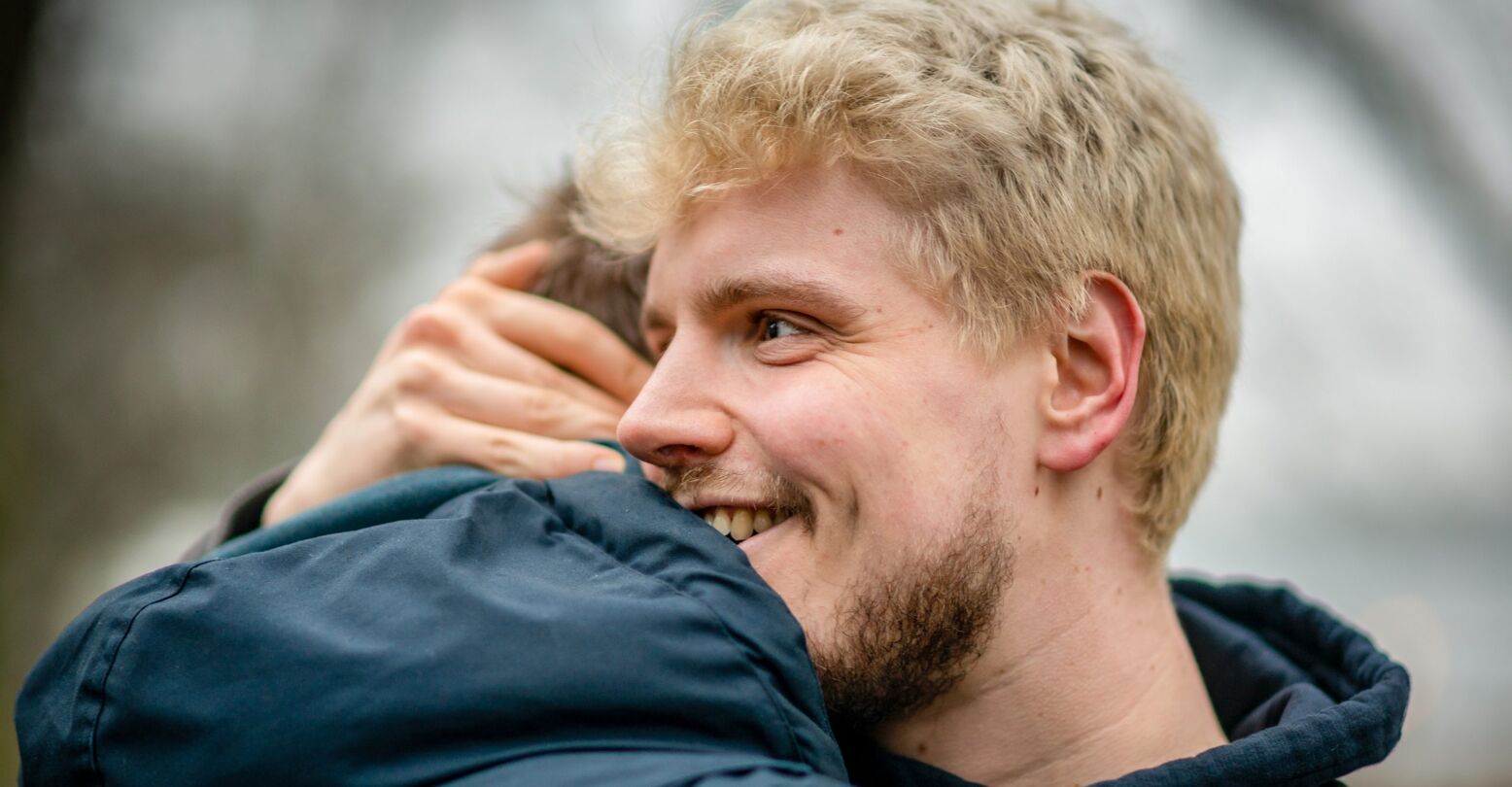 A healthy man living with HIV hugging his friend outside at a park in Hamburg, Germany