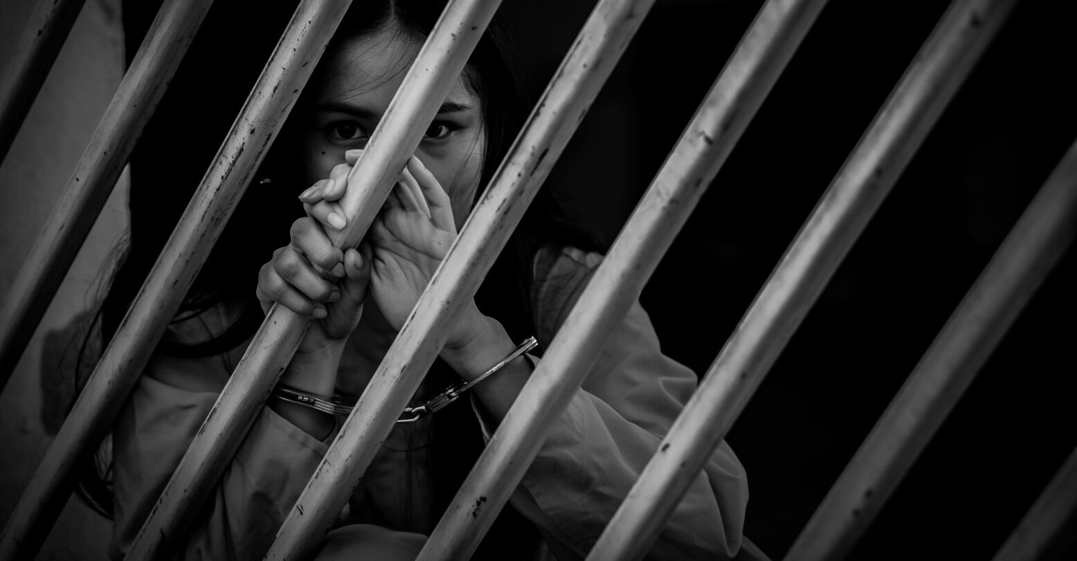 Women wearing handcuffs behind bars/imprisoned