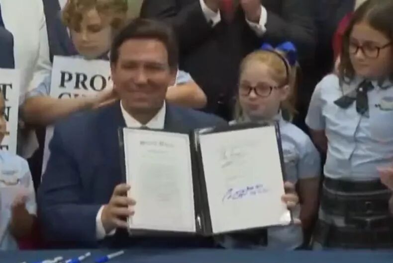 Florida governor signs “Don’t Say Gay” bill while surrounded by kids holding anti-LGBTQ signs