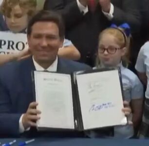 Florida governor signs “Don’t Say Gay” bill while surrounded by kids holding anti-LGBTQ signs