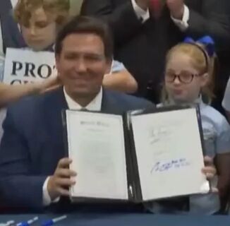 Florida governor signs “Don’t Say Gay” bill while surrounded by kids holding anti-LGBTQ signs