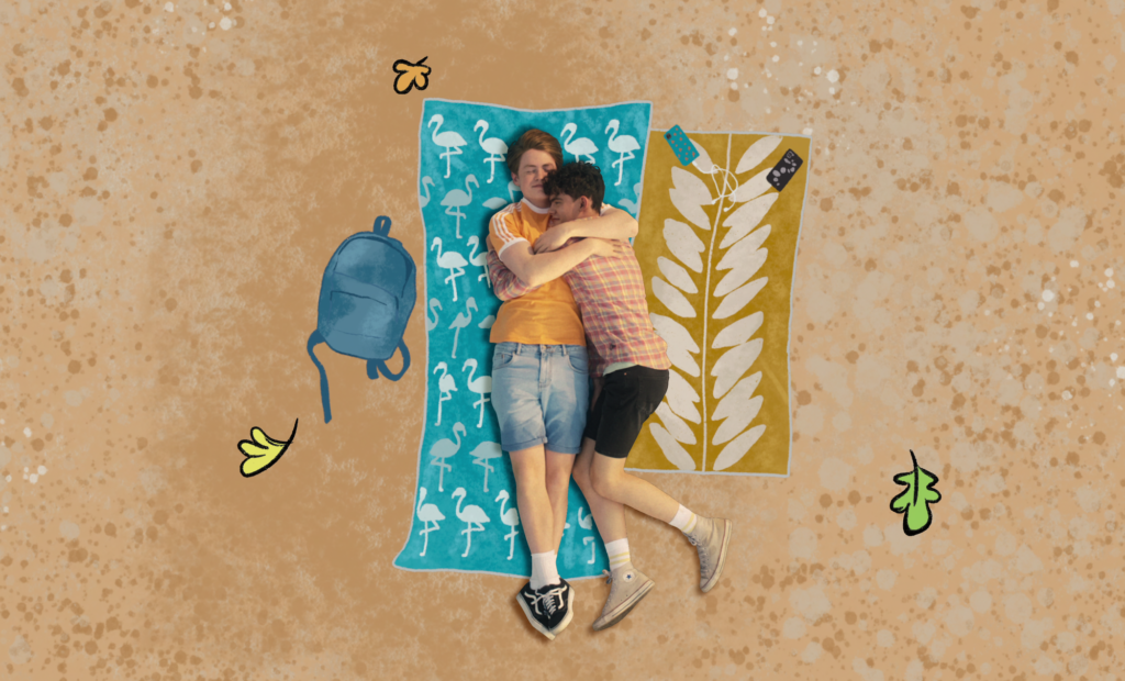 Kit Conner and Joe Locke lay on the beach in a scene from Heartstopper