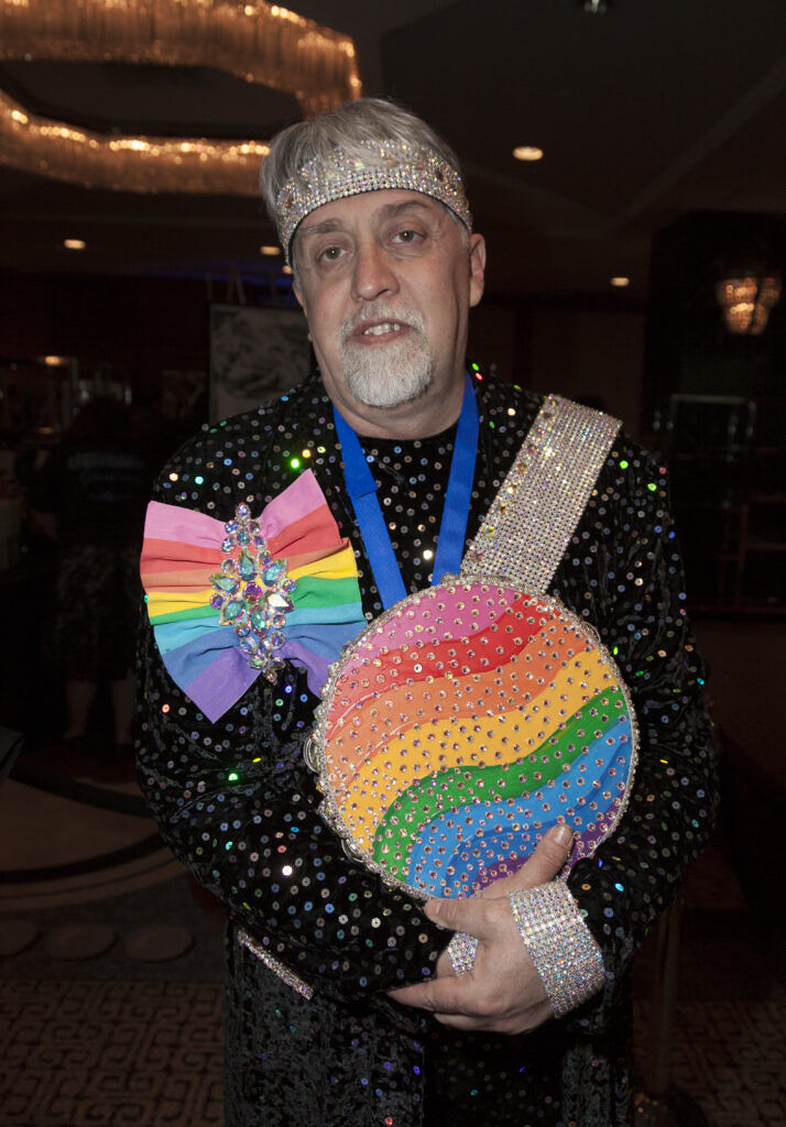 Gilbert Baker, creator of the original Pride rainbow flag, wearing a brooch and clutch in the original 8 stripes attends an event in NYC.
