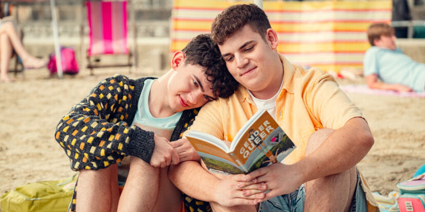 Joe Locke as Charlie Spring comforting Tobie Donovan as Isaac Henderson while they read the book Gender Queer: A Memoir